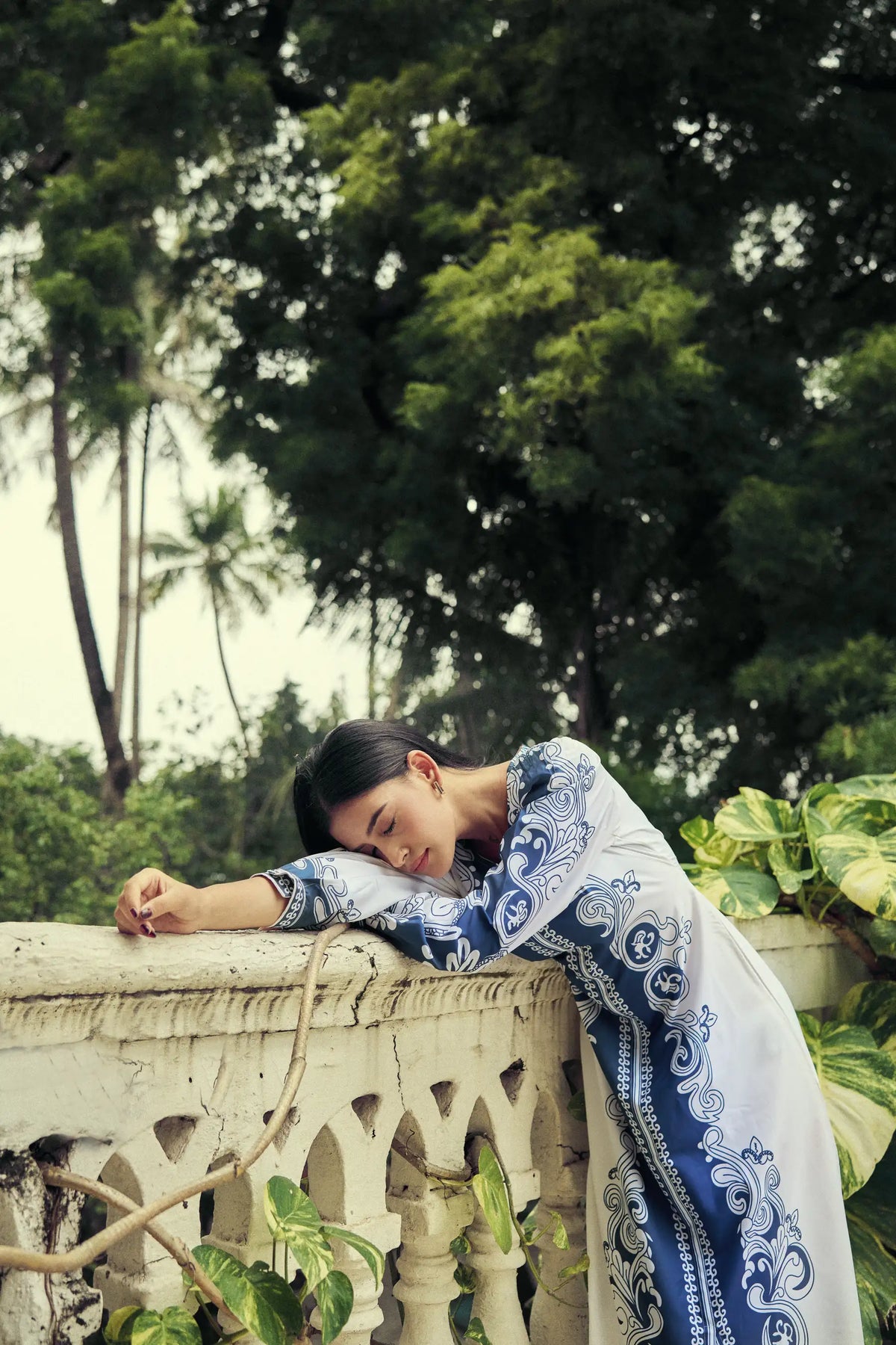 Model resting on a balcony rail in a blue and white printed set
