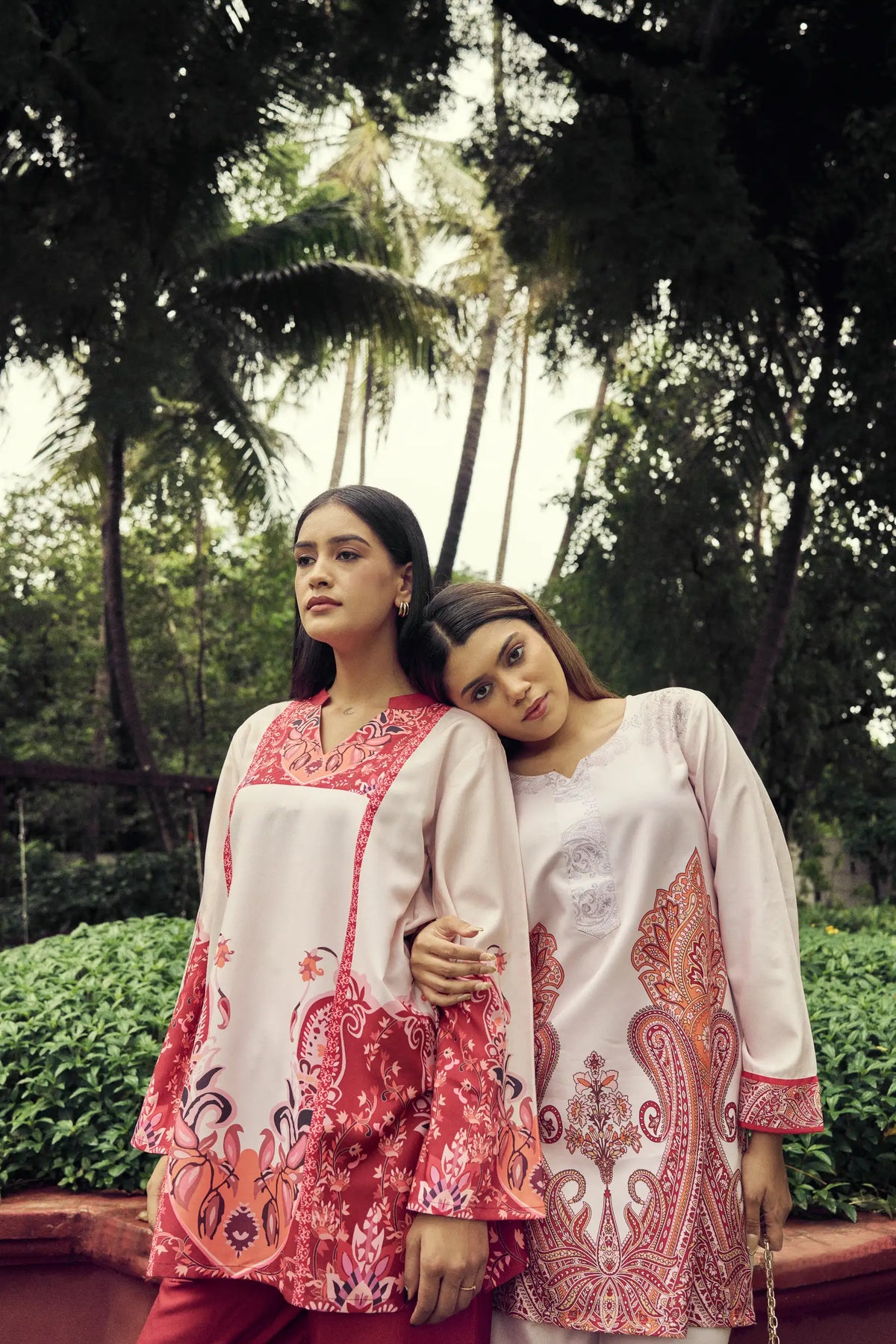 Two models in crimson paisley sets leaning together