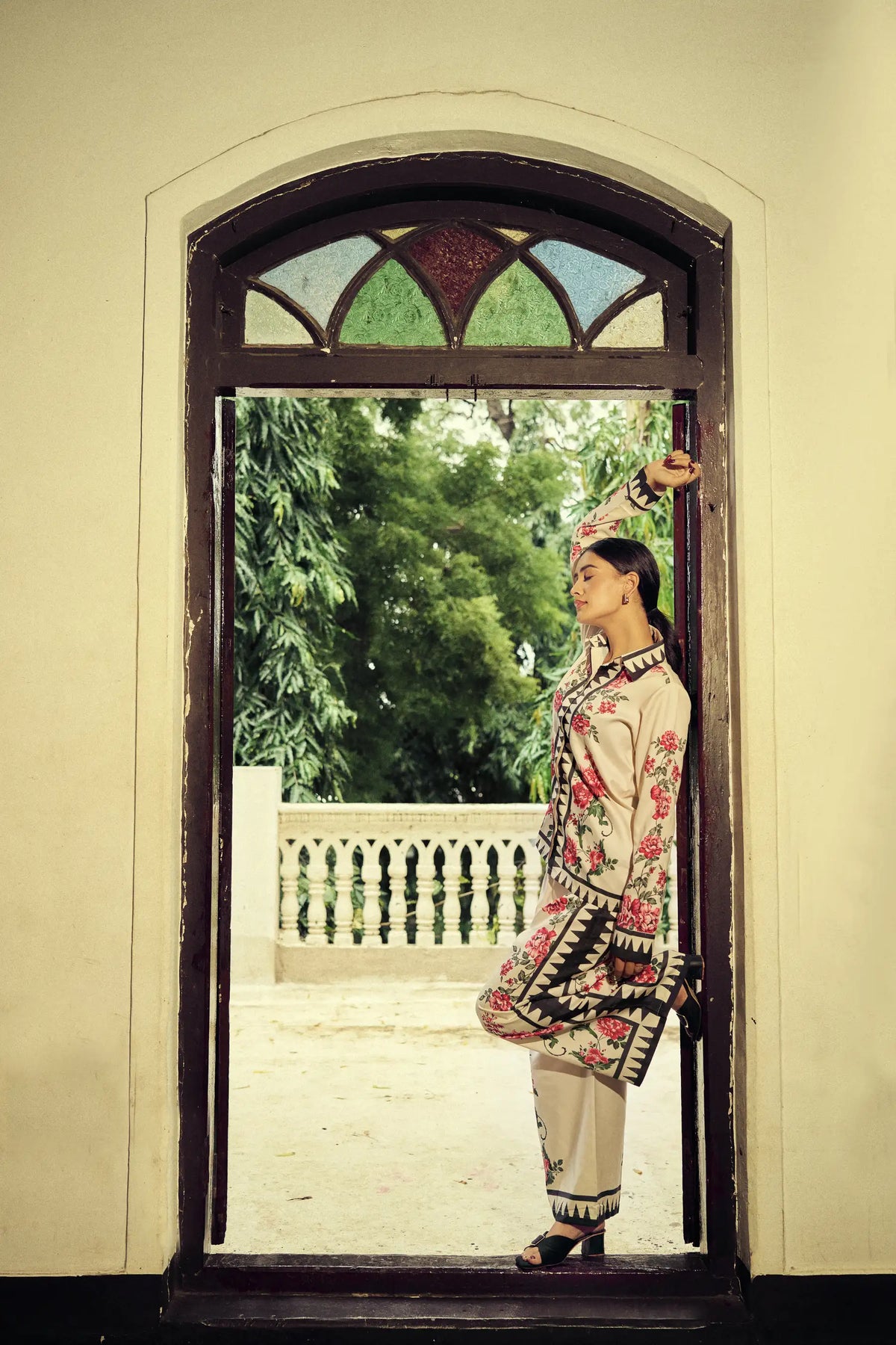 Model in a doorway with a hand raised