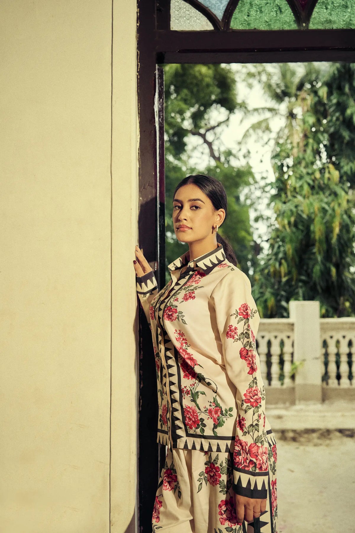 Model leaning in a sunlit doorway in a printed co-ord set