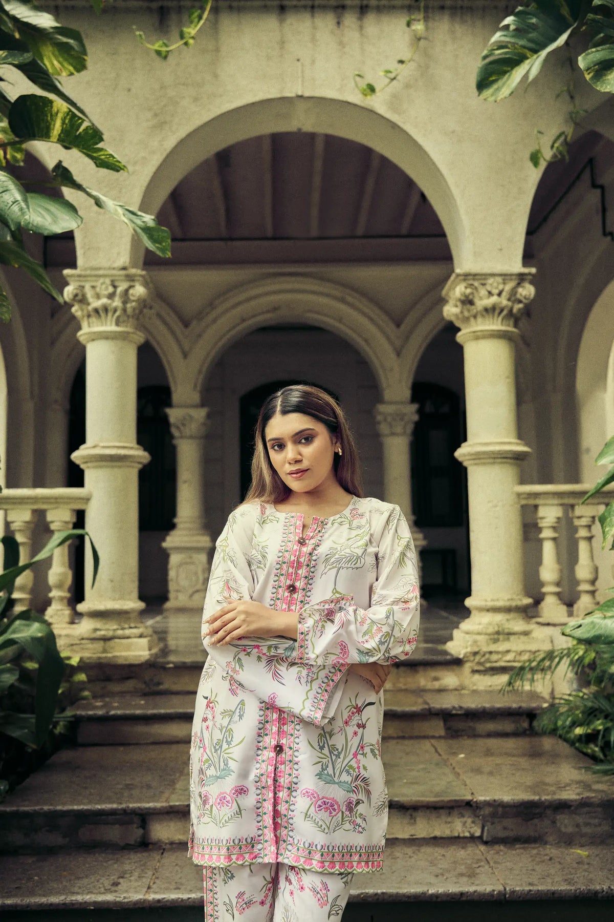 Model standing under the arches of an old bungalow