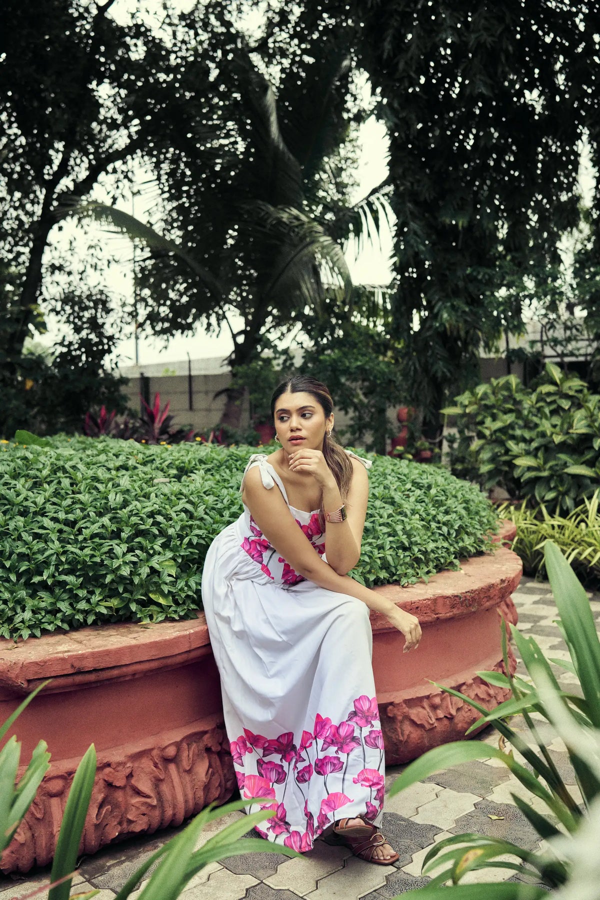 Model seated on a terracotta garden wall in a poppy maxi dress