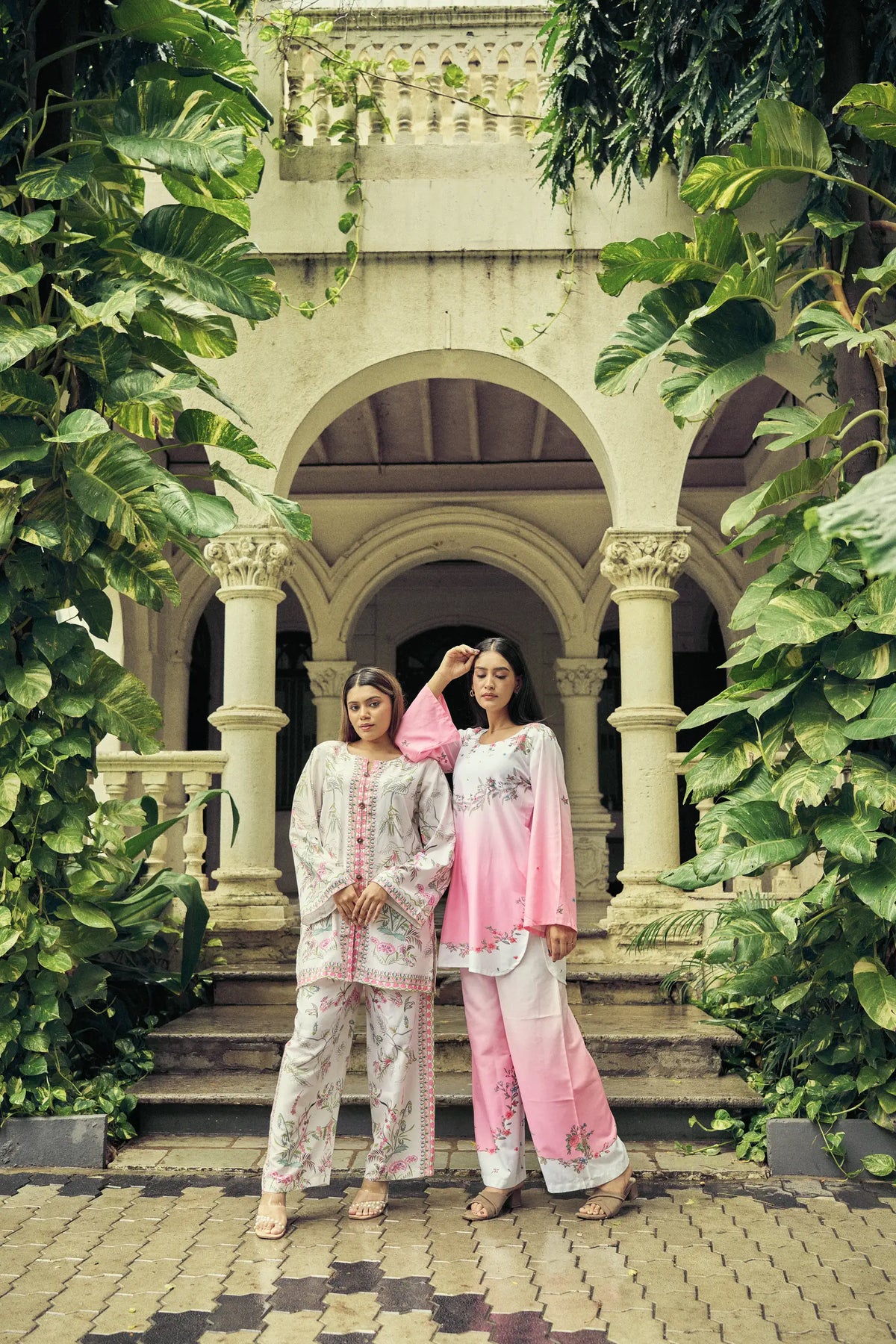 Two models in pink and white sets on veranda steps