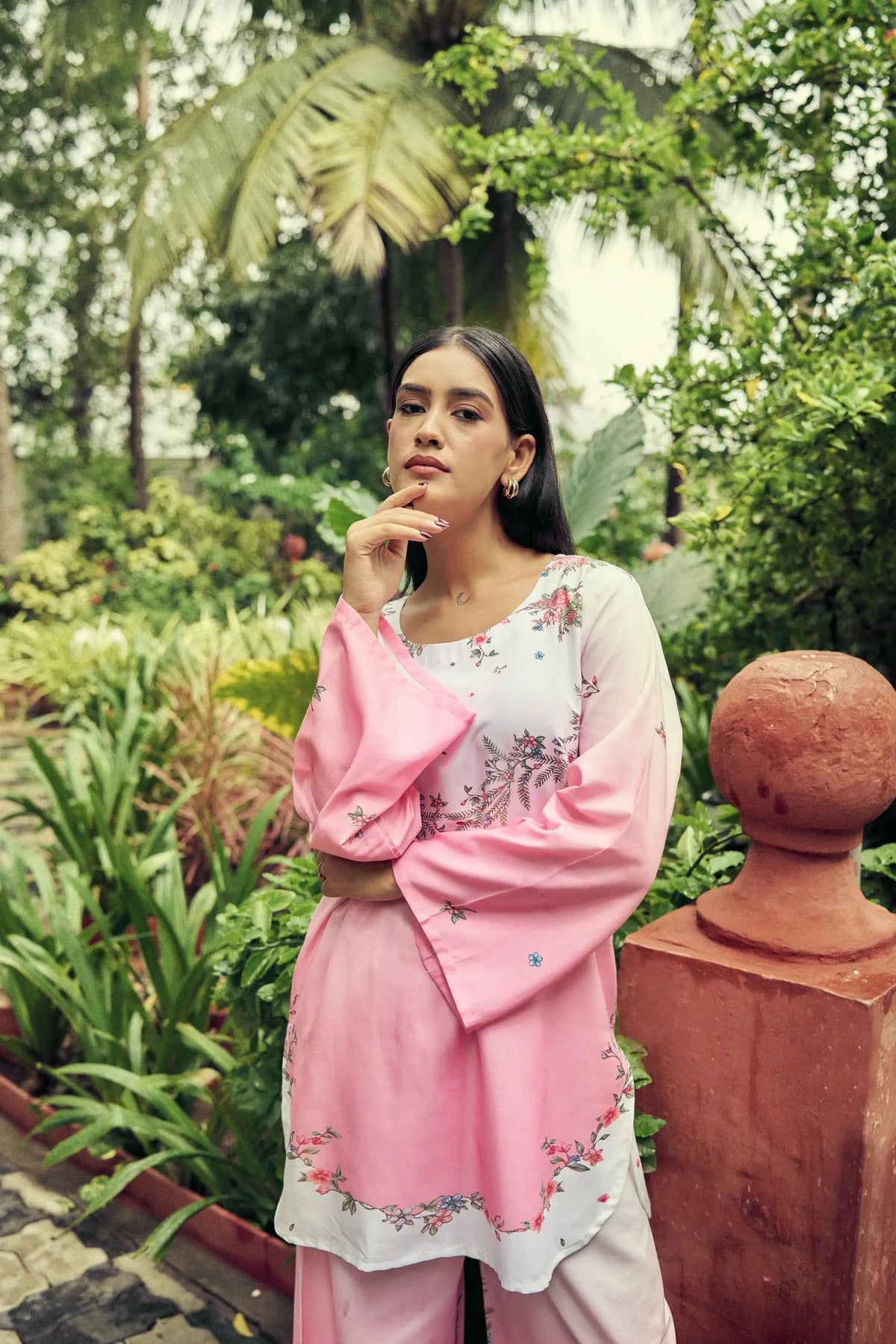 Model in a pink ombre top with a hand raised